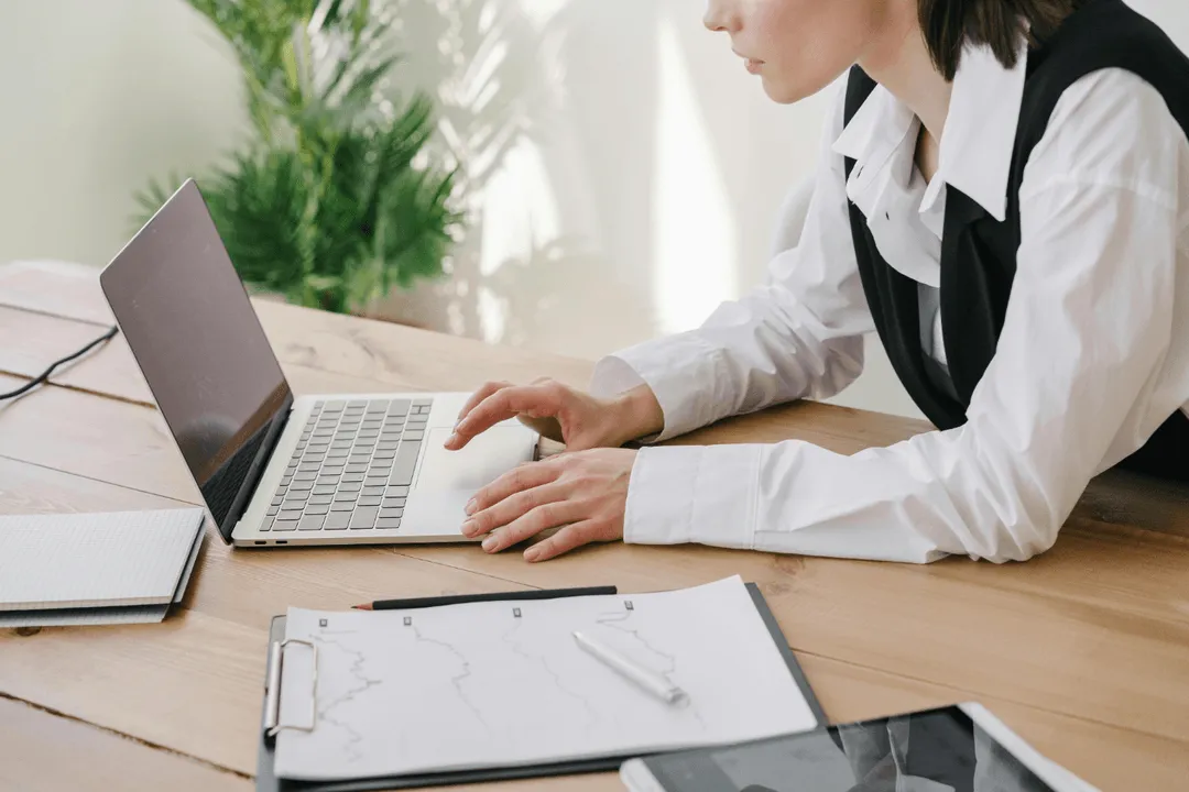 A Woman Wearing a White Long Sleeved Shirt Using a Laptop